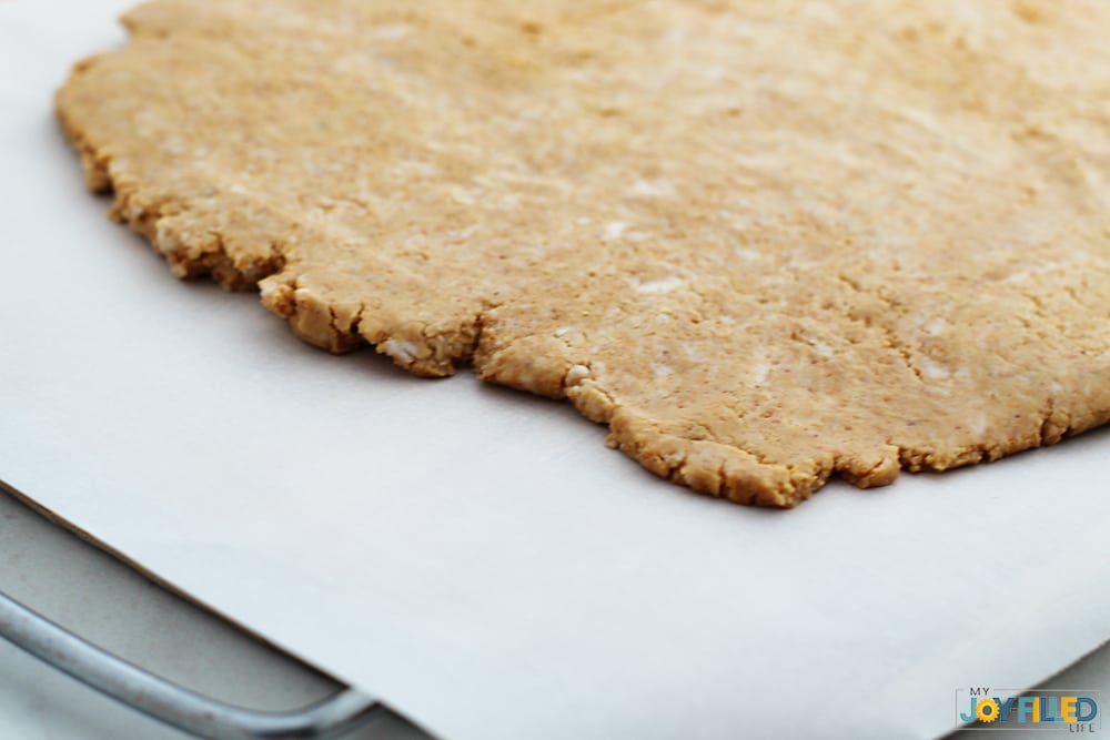 Rolling out homemade copycat Reese's hearts onto parchment paper