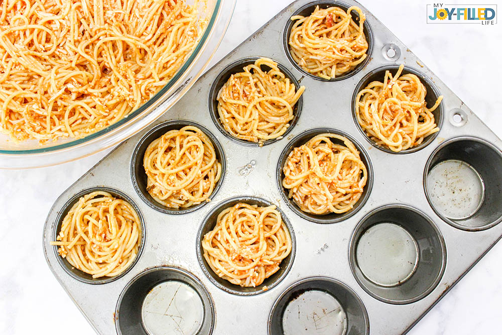 fill muffin tins with spaghetti for spaghetti and meatball cups