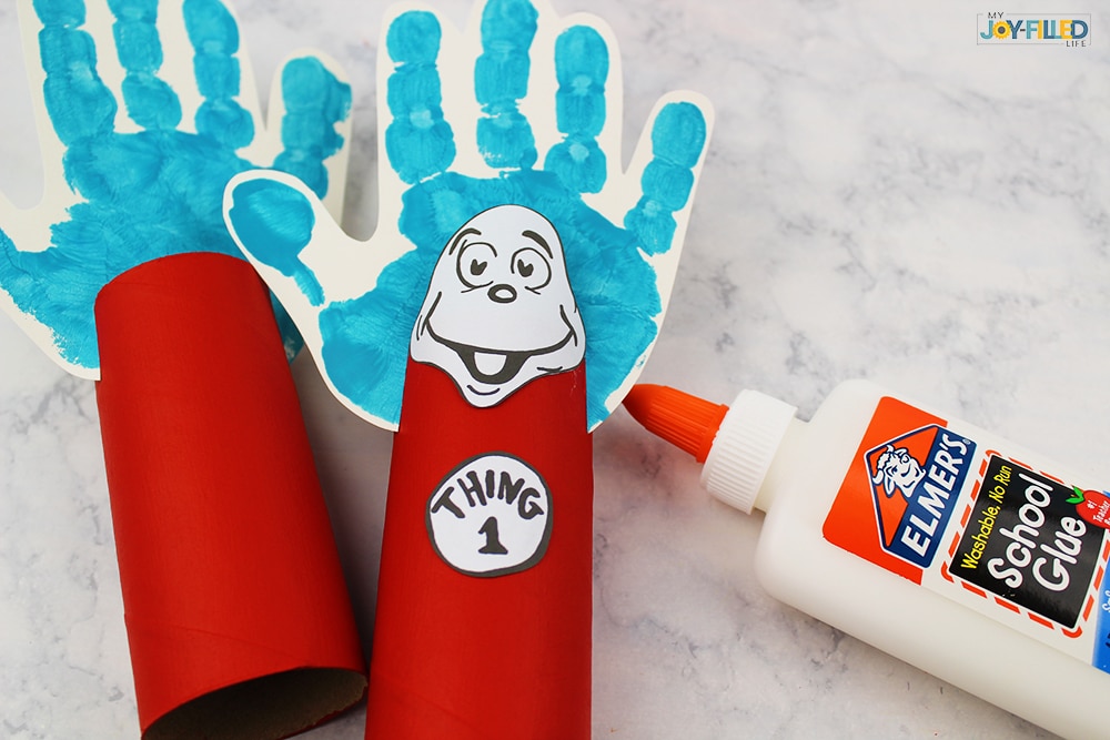 Thing 1 and Thing 2 craft almost complete with kid handprint and painted toilet paper roll, glue