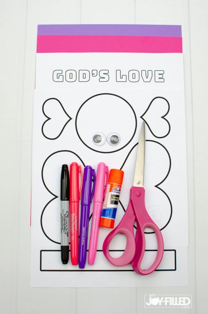 Supplies for Valentine craft including pink and purple card stock, printable template, googly eyes, markers, glue stick, scissors.