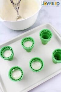 Adding cake mix to green ice cream cones